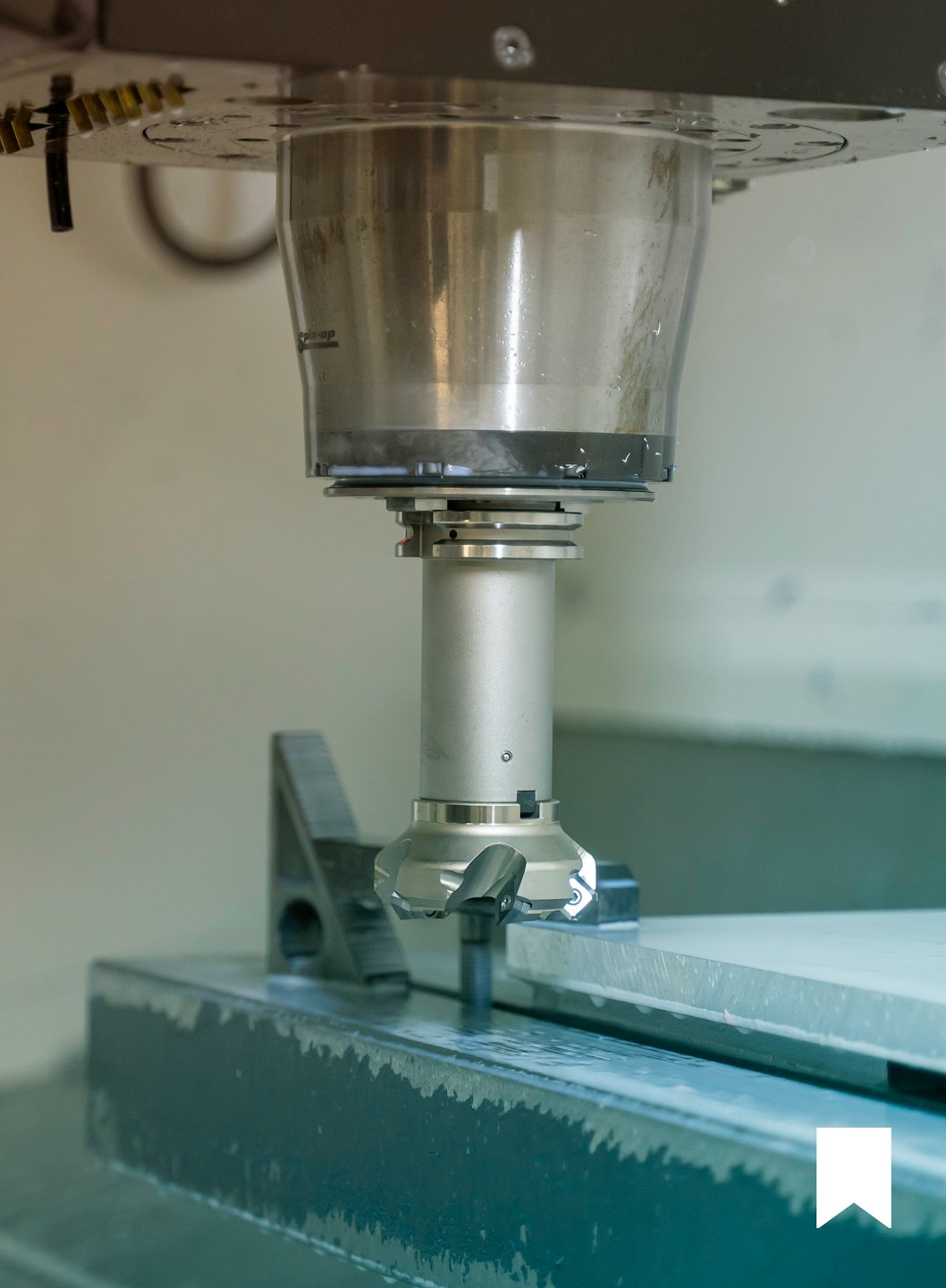 CNC-Fräsmaschine bearbeitet Metallwerkstück mit Kühlmittel.