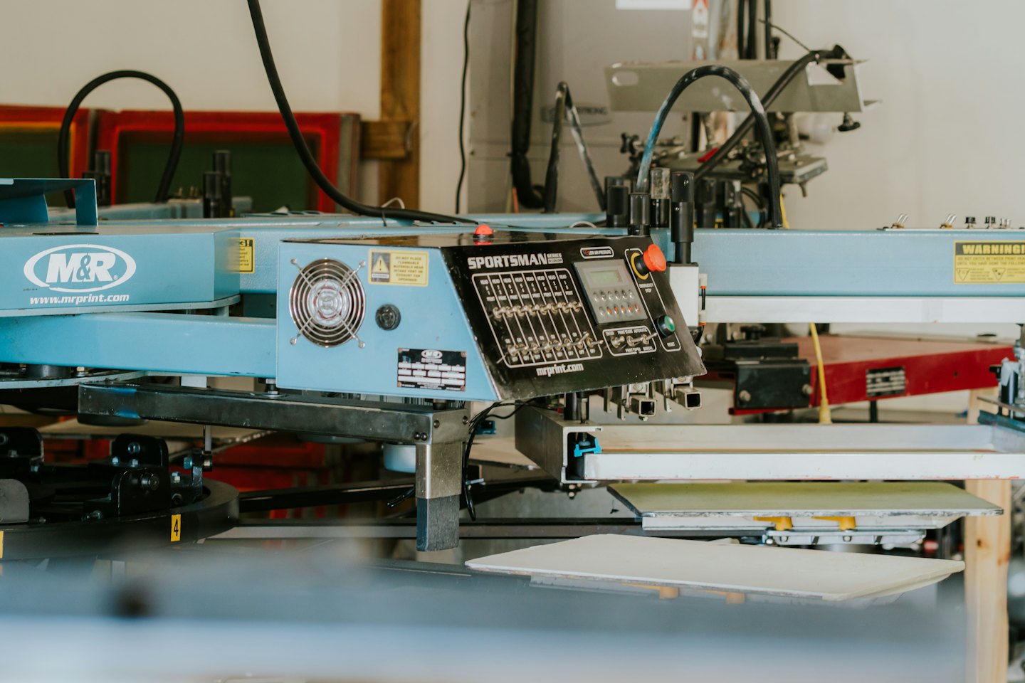 Bedienfeld einer automatischen Siebdruckmaschine in einer Werkstatt.