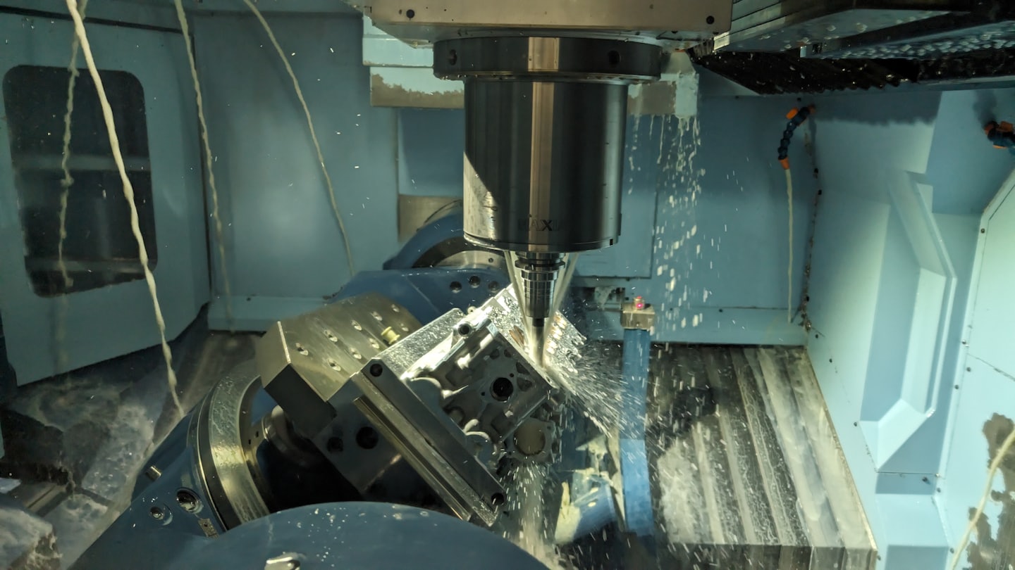 CNC-Fräsmaschine sprüht Kühlmittel auf Metallwerkstück.