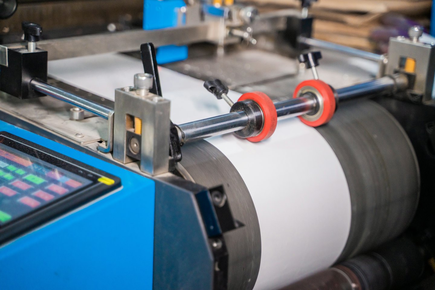 Industrielle Druckmaschine führt weißes Papier durch Walzen.